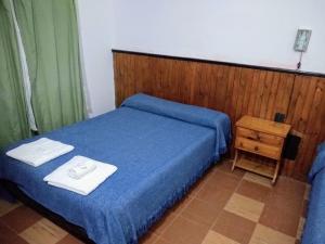 Un dormitorio con una cama azul con toallas. en Megaró, en Santa Teresita