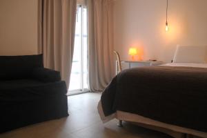 a bedroom with a bed and a chair and a window at Hotel Florinda in Punta del Este