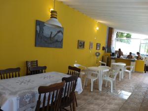 a restaurant with white tables and chairs and a yellow wall at Guaraú Praia Suítes in Peruíbe