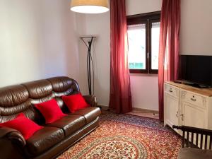 a living room with a brown leather couch and red pillows at Lines of Wellignton in Torres Vedras