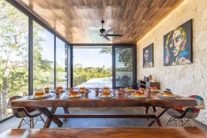 a large wooden table in a room with windows at Villa LaGú Masterpiece Tulum Jungle 5BR Pool & Spa in Tulum