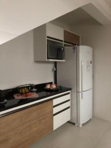 a kitchen with a white refrigerator and wooden cabinets at Guest House Recanto da Montanha in Cunha