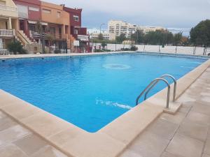 duży niebieski basen obok niektórych budynków w obiekcie Apartamento Barbacoa, Piscina y playa w mieście Puebla de Farnals