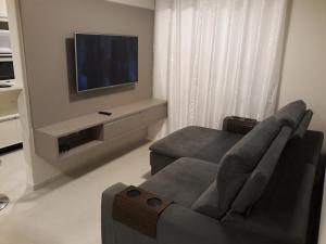 sala de estar con sofá y TV en Apt Interiro Praia de Itapema, en Itapema