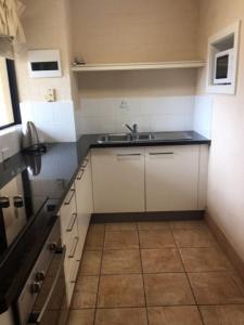 a kitchen with white cabinets and a sink at Riverview Holliday villa with River Views and Pool in Kalbarri