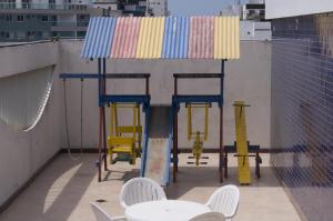 uma mesa colorida e cadeiras no topo de um edifício em Apart Guarapari Residence - Areia Preta em Guarapari