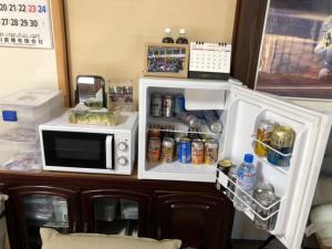 a refrigerator with its door open next to a microwave at Rider & Guest House Kazeyoubi in Fukuyama