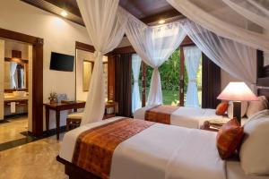 a hotel room with two beds and a window at Bali Tropic Resort & Spa - CHSE Certified in Nusa Dua