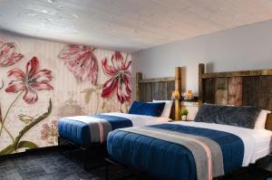 dwa łóżka w pokoju z kwiatami na ścianie w obiekcie Vintage Block Inn & Suites w mieście Okoboji