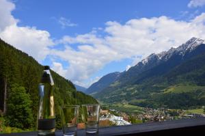 een fles wijn en glazen op een tafel met bergen bij Grenzberg Appartements in Bad Gastein