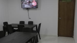 a dining room with a table and chairs and a television at Puerto Caribe Hostal in Guachaca
