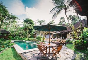 an outdoor table with an umbrella next to a swimming pool at Heaven in Bali in Penginyahan