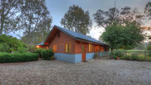 a small wooden cabin in a yard with trees at Alpine Riverside Accommodation in Myrtleford
