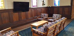 een kamer met stoelen, een tafel en een tv bij Barrington Church B&B in Barrington