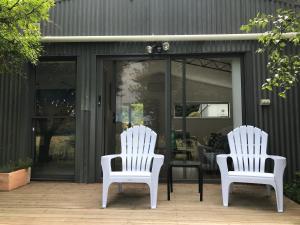 dos sillas blancas sentadas frente a una tienda en Langleys Port Campbell Hobby Farm, en Port Campbell