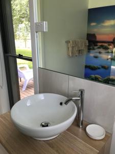 a white sink in a bathroom with a painting on the wall at Langleys Port Campbell Hobby Farm in Port Campbell