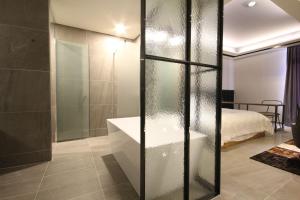 a bathroom with a glass shower and a bed at Hotel Eco stay in Jeonju