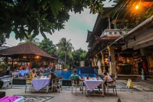 un grupo de personas sentadas en mesas junto a una piscina en Legian Village Hotel - CHSE Certified, en Legian