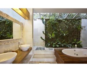 a bathroom with two sinks and a bath tub and a plant at Sunset Paradise Villa Uluwatu in Uluwatu