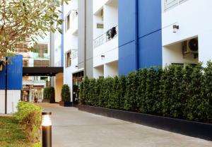 a blue and white building with bushes next to a sidewalk at The Resto in Udon Thani