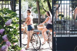 two girls riding bikes in front of a gate at Casina Le Conserve in Cesenatico