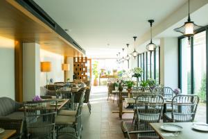 a restaurant with tables and chairs and windows at Lavana Hotel Chiangmai in Chiang Mai
