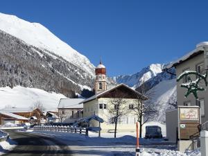 ein Gebäude mit einem Uhrturm im Schnee in der Unterkunft Apart Tyrol in Umhausen