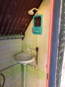 a small bathroom with a sink and a tv at Beach Shack Chalet - Garden View Aframe Small Unit in Tioman Island