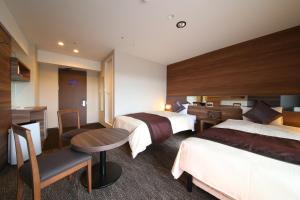 Habitación de hotel con 2 camas y escritorio en The Hedistar Hotel Narita, en Narita