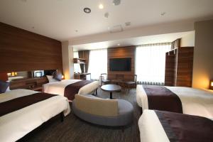 a hotel room with three beds and a television at The Hedistar Hotel Narita in Narita