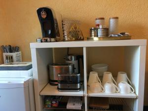 een witte plank met kopjes en een koffiezetapparaat bij Gästezimmer Hortensie in Weil der Stadt