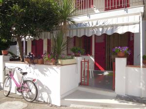 un vélo rose garé devant un bâtiment dans l'établissement Appartamento In Riva Al Mare con Posto Auto E Disponibilità Bicicletta, à Mascali