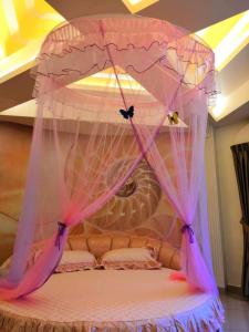 a bed with a canopy with pink curtains on it at Rocky Farm in Ipoh