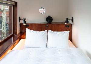 a bedroom with a bed with white sheets and a window at SWEETS - Zeilstraatbrug in Amsterdam +10 photos