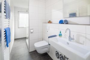 ein weißes Badezimmer mit Toilette und Waschbecken in der Unterkunft Ferienhaus an der Karlstraße in Norderney