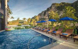 una piscina en un complejo con sillas y sombrillas en Andaman Breeze Resort - SHA Plus en Ao Nang