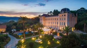 a view of a building with palm trees and lights at Hôtel l'Orangeraie in La Croix-Valmer