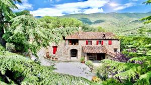 a large stone house with red doors on a mountain at Borgo Solamore in Cortona