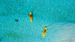 three people in yellow kayaks in the blue water at Filitheyo Island Resort in Filitheyo