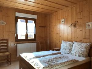 a bedroom with a bed with wooden walls and a window at Les Berges de l'Ohmbach in Soultzmatt