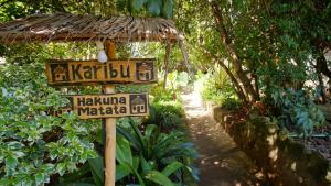 ein Straßenschild in einem Garten mit einem Schild in der Unterkunft Karen Little Paradise in Nairobi