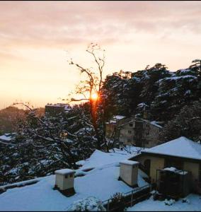 zimowy zachód słońca nad miastem z śniegiem na ziemi w obiekcie The Thistle Lodge w mieście Shimla