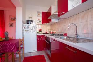 eine Küche mit roten Schränken und einem weißen Kühlschrank in der Unterkunft Apartments M&J in Supetar