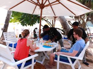 grupa ludzi siedzących przy stole pod parasolem w obiekcie Fresh Wave Mirissa - Beach Front w mieście Mirissa