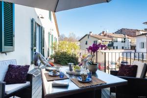 una mesa y sillas en un balcón con sombrilla en Varenne Open Terrace and Private Parking, en Lucca