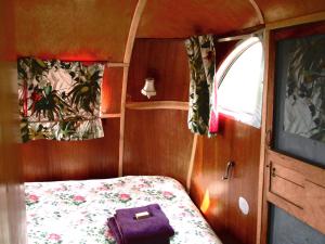 a small room with a bed with a purple bag on it at Belrepayre Airstream Camp in Manses
