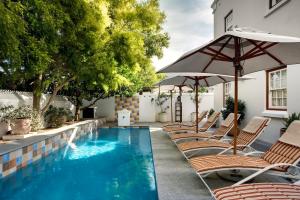 a swimming pool with chairs and an umbrella at Coopmanhuijs Boutique Hotel & Spa in Stellenbosch