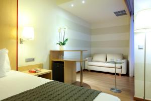 Habitación de hotel con cama, escritorio y sofá en Eurostars Centrum Alicante en Alicante
