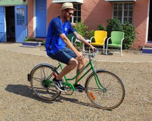 Un uomo che cavalca una bicicletta verde per strada di Blue Swallow Motel a Tucumcari