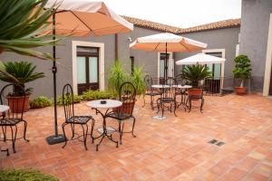 a patio with tables and chairs and umbrellas at Dimora De Mauro in Catania